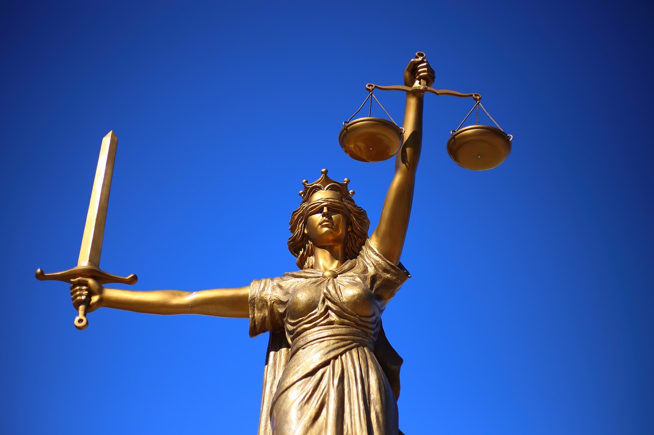 Themis, the Goddess of justice, holding scales against a blue sky