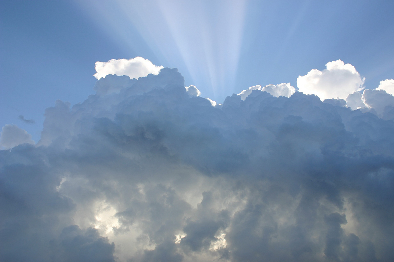 Beams of sunlight emanating from behind billowing clouds.